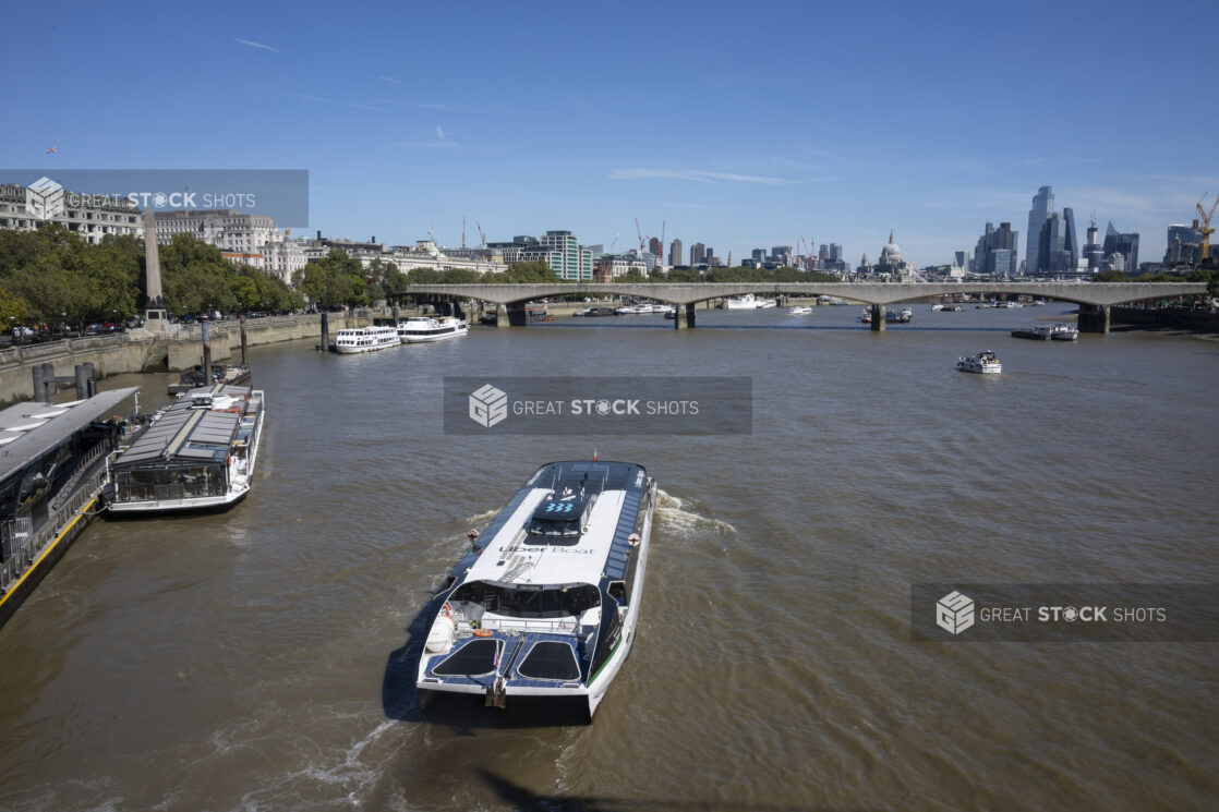 An Uber Boat and Other Tourist Boats Floating on the River Thames in London, England