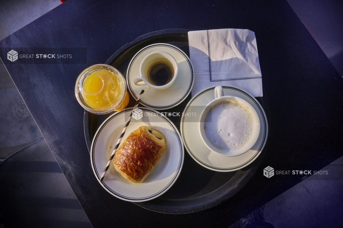 Overhead shot of continental breakfast on a tray with coffee, pastry and orange juice