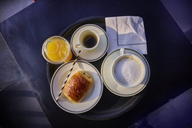 Overhead shot of continental breakfast on a tray with coffee, pastry and orange juice