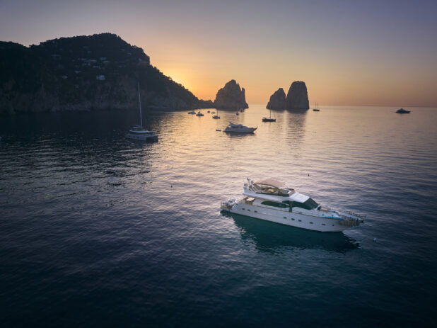 Sunrise/sunset views of the coastline in Capri, Italy, with yachts and hillside