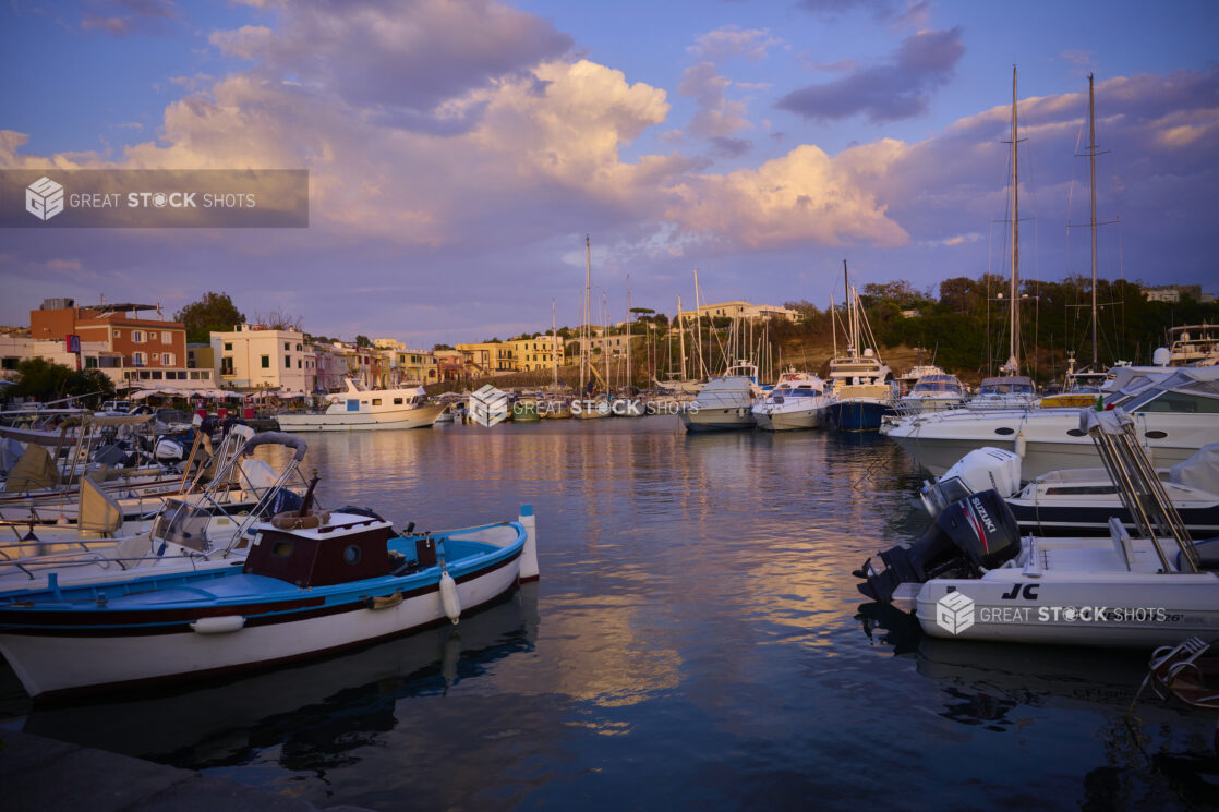 Yachts and Boats at an Inner Harbour of Italian Costal Town during a Beautiful Sunset with the town in the backgrount