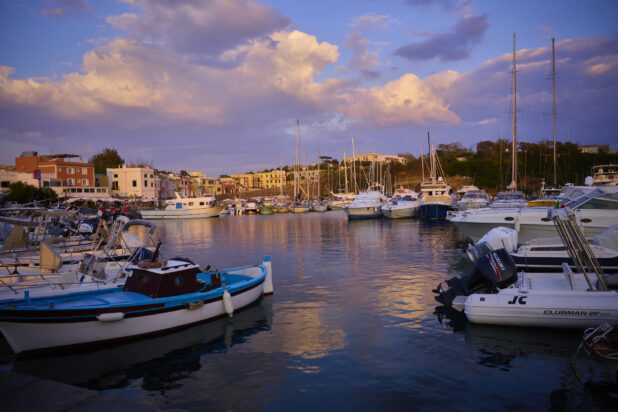 Yachts and Boats at an Inner Harbour of Italian Costal Town during a Beautiful Sunset with the town in the backgrount