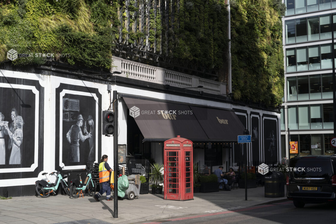 Wide Shot Lifestyle Shot of street cafe with greenery on building and red telephone box on sidewalk