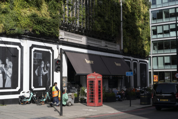 Wide Shot Lifestyle Shot of street cafe with greenery on building and red telephone box on sidewalk