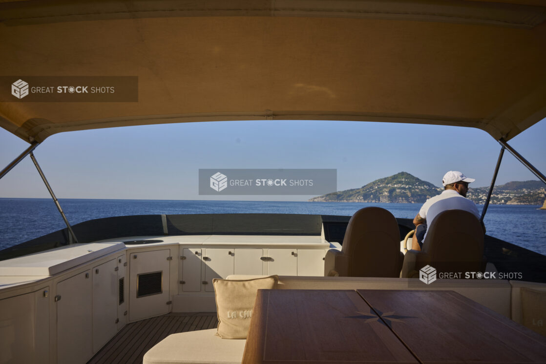 Yacht Captain driving on the Ocean along the Italian Coastline with cliffs in the background