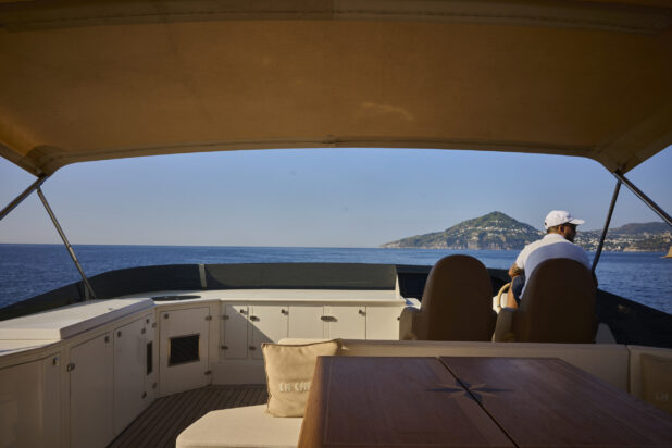 Yacht Captain driving on the Ocean along the Italian Coastline with cliffs in the background