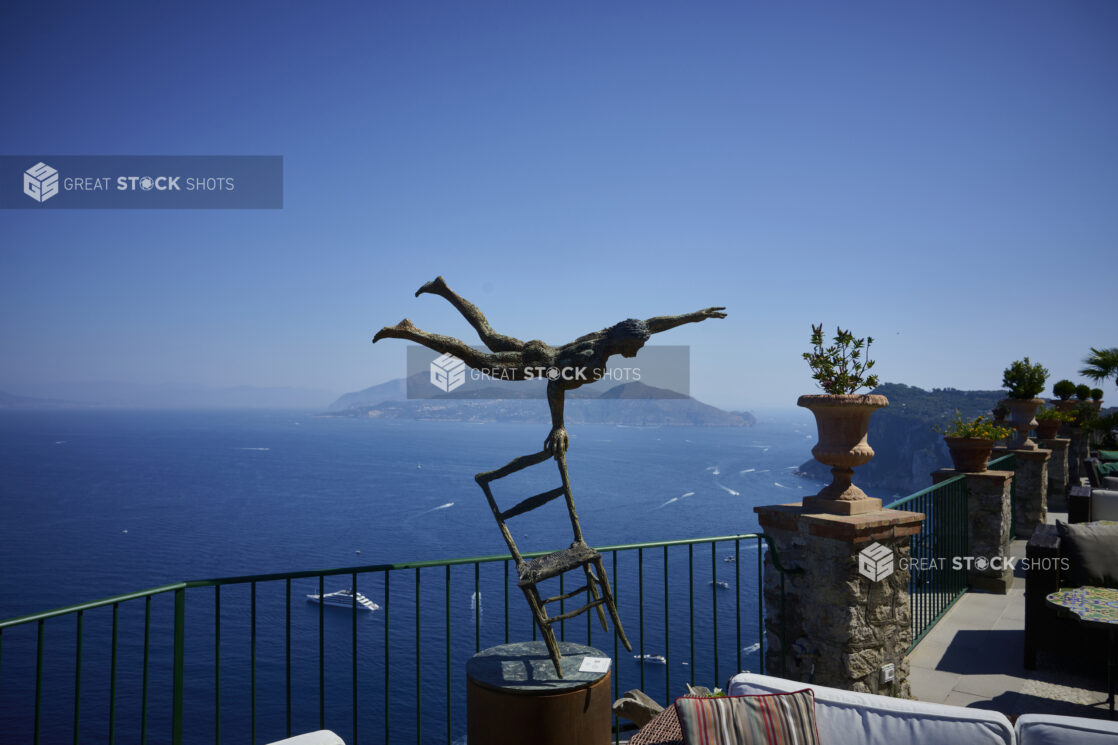 Bronze Art Statue on Outdoor Terrace overlooking Italian Coastline with beautiful Cliffs in the background surrounded by perfectly blue ocean