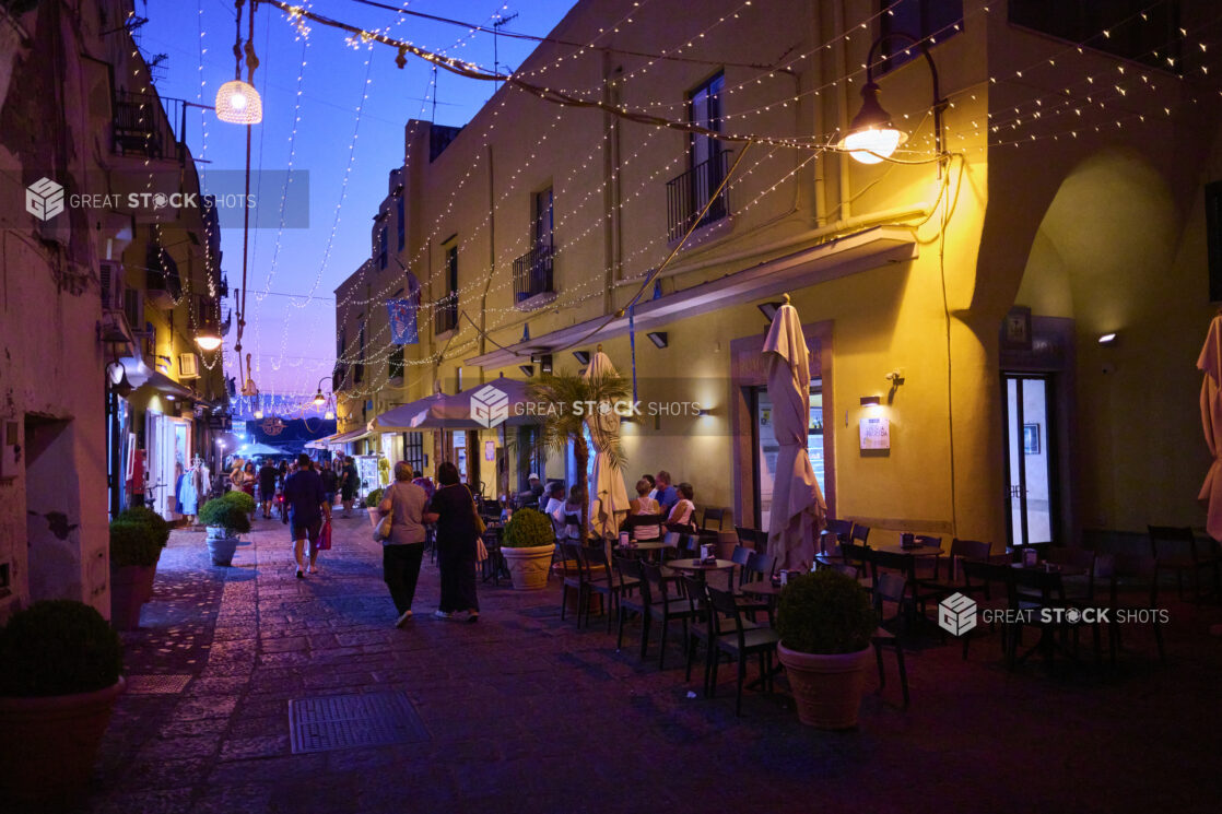 Italian Cafe Outdoor Patio at Dusk with overhead String Lights and Cobblestone roads