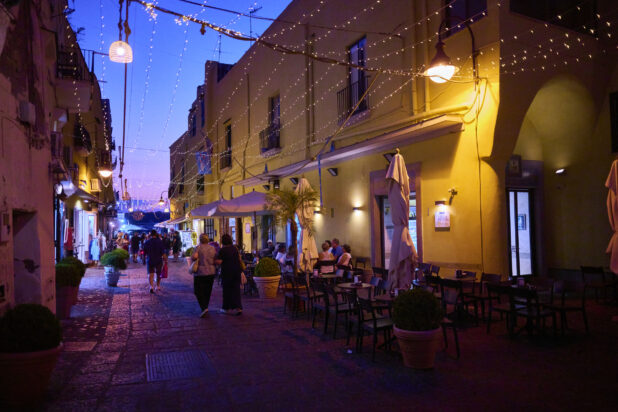 Italian Cafe Outdoor Patio at Dusk with overhead String Lights and Cobblestone roads