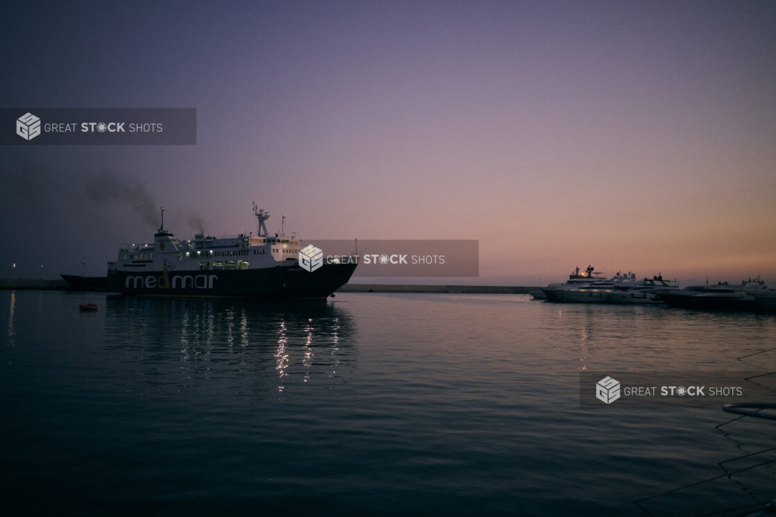 Industrial Ship Sailing on a Calm Ocean at Dusk Out of a Harbour