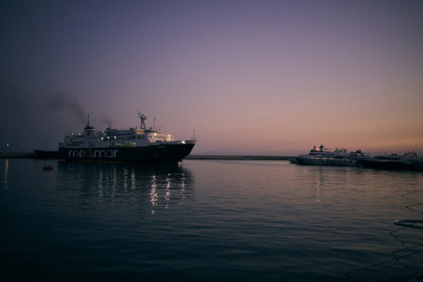 Industrial Ship Sailing on a Calm Ocean at Dusk Out of a Harbour