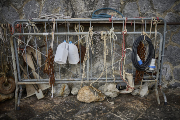 Fishing gear/ropes tied to a barrier against a stone wall