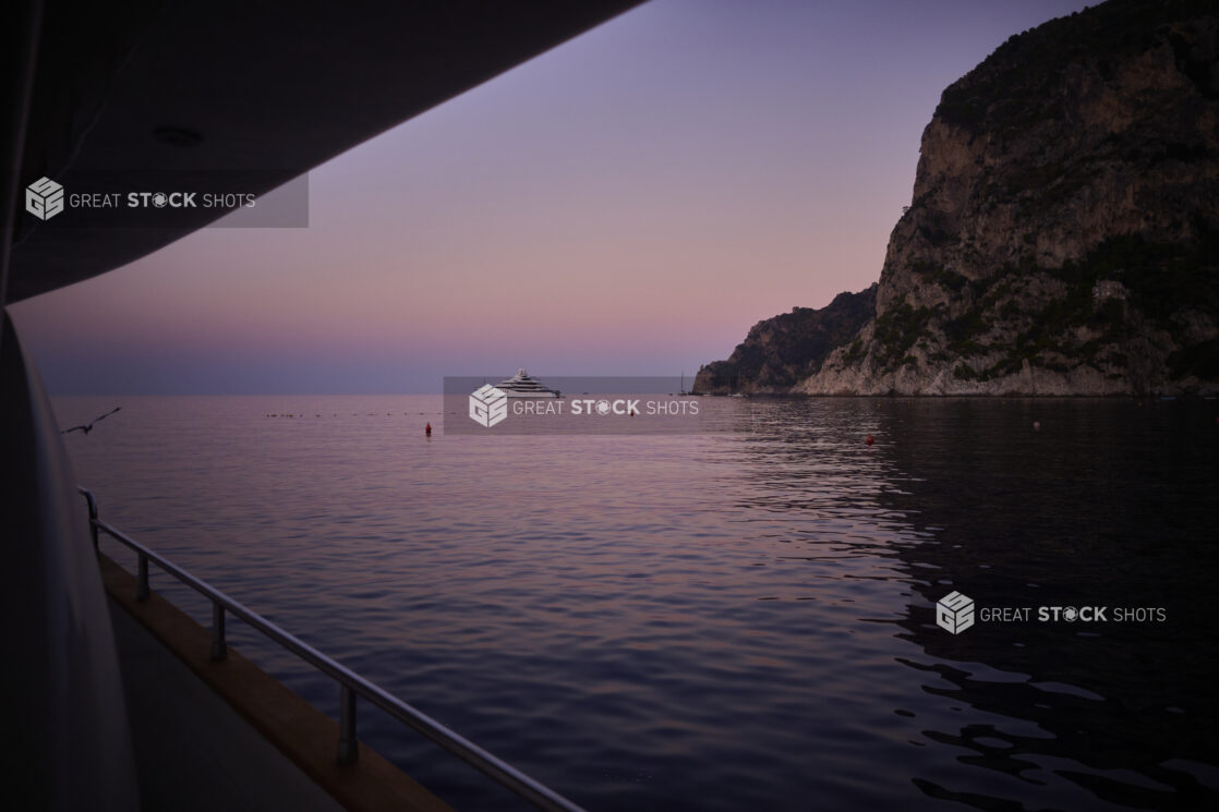 Dusk view of a hillside and a yacht from a yacht/boat on the Mediterranean sea