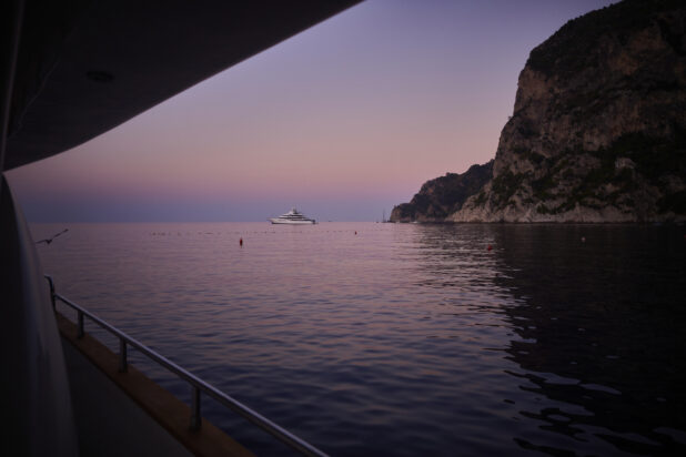 Dusk view of a hillside and a yacht from a yacht/boat on the Mediterranean sea