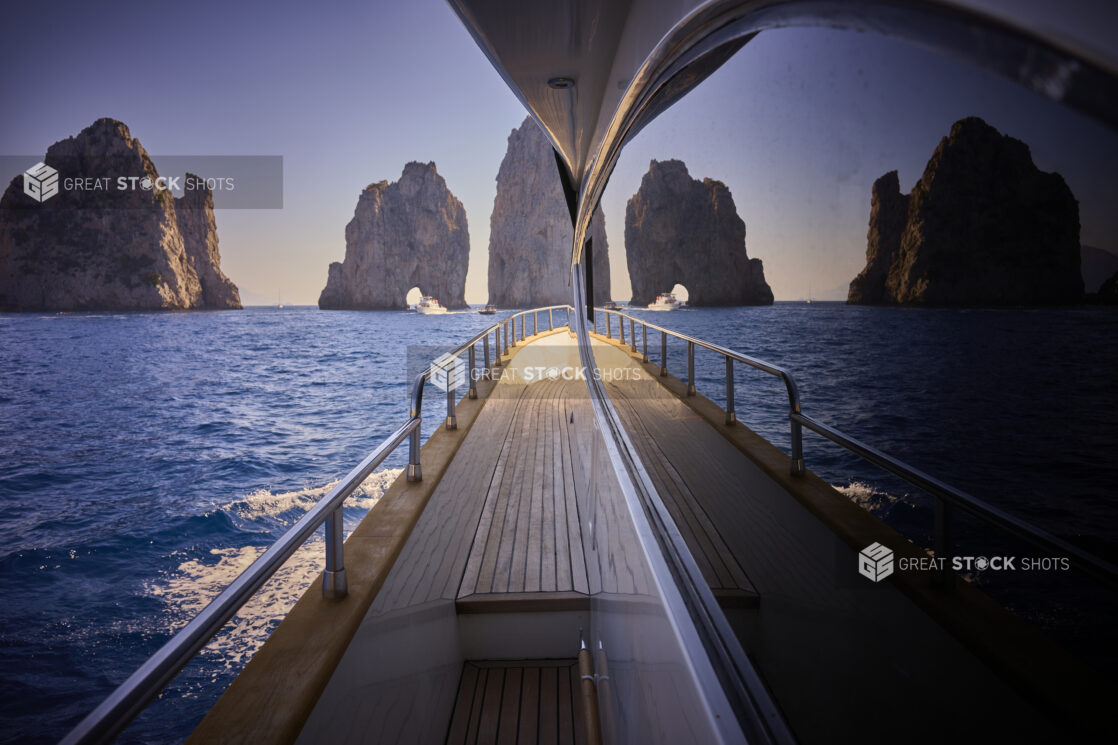 View of the sea with boats, Faraglioni rock formations and mountainside reflected off a window on a yacht, Capri, Italy