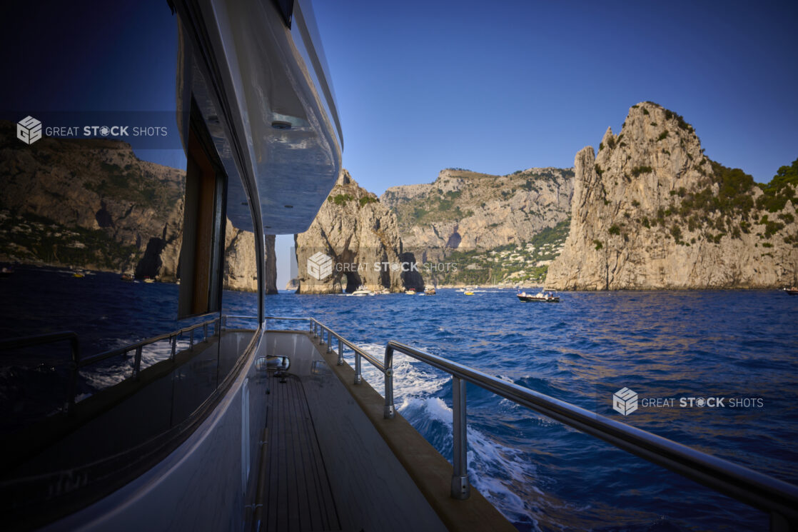 Medium Shot of the Side Walkway of a Yacht with the Ocean, Italian Coast and Mountains Reflected in the Window