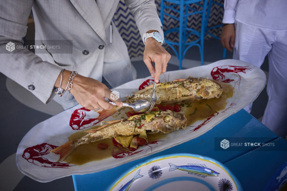 Whole fried fish on a platter being served with bright blue table and chairs, Mediterranean vibe