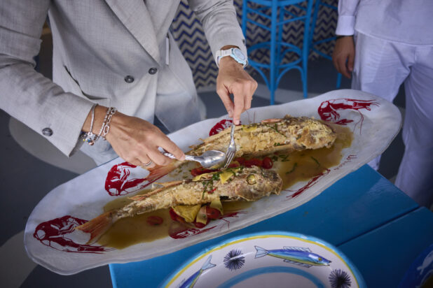 Whole fried fish on a platter being served with bright blue table and chairs, Mediterranean vibe
