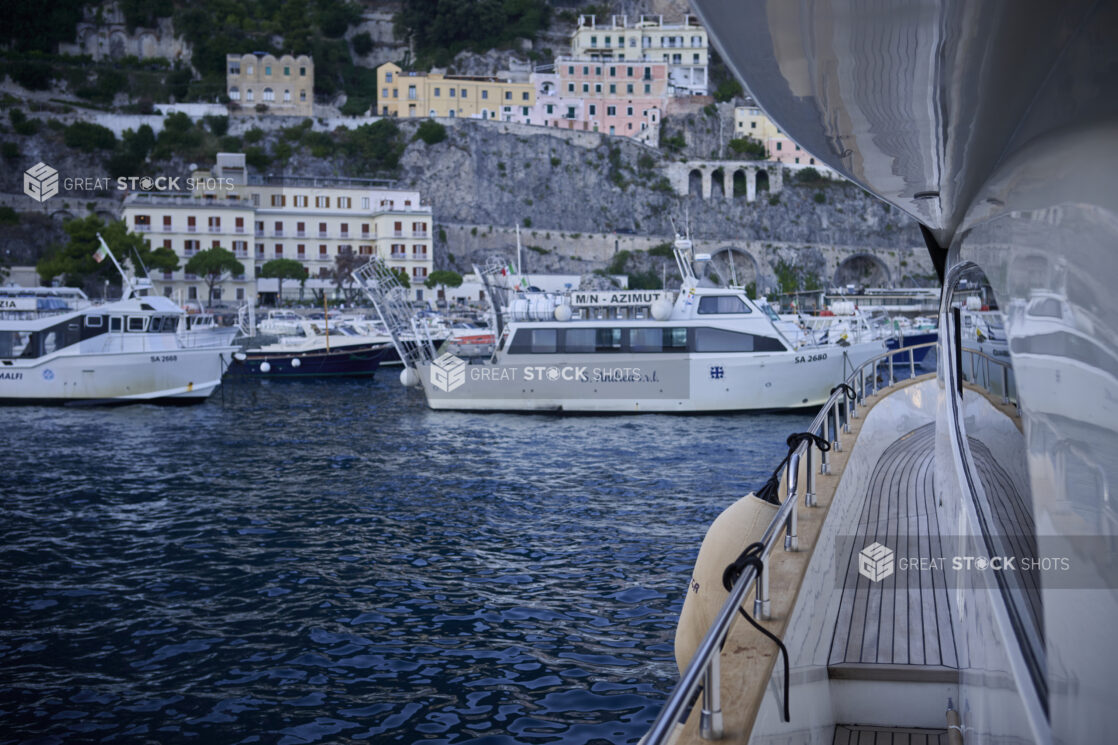 View from a yacht looking at a harbour with other boats and yachts and the hillside, on the Amalfi coast, Italy