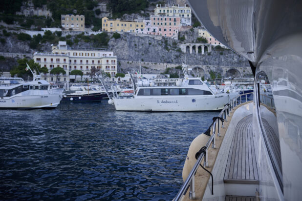 View from a yacht looking at a harbour with other boats and yachts and the hillside, on the Amalfi coast, Italy