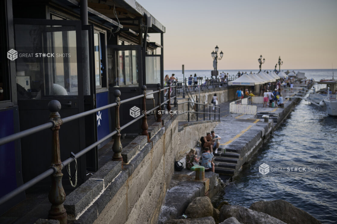 Pier on the Amalfi coast, Italy, with people, tents and boats