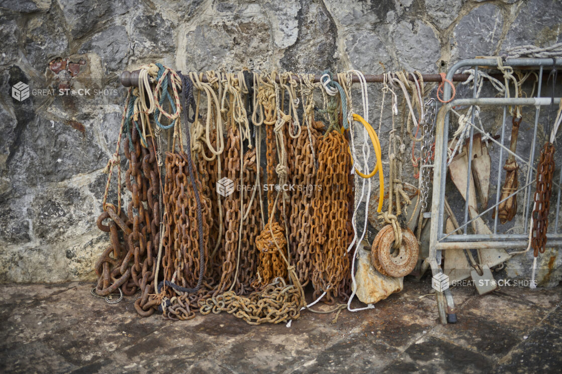 Fishing ropes, chains and weights against a stone wall in Italy