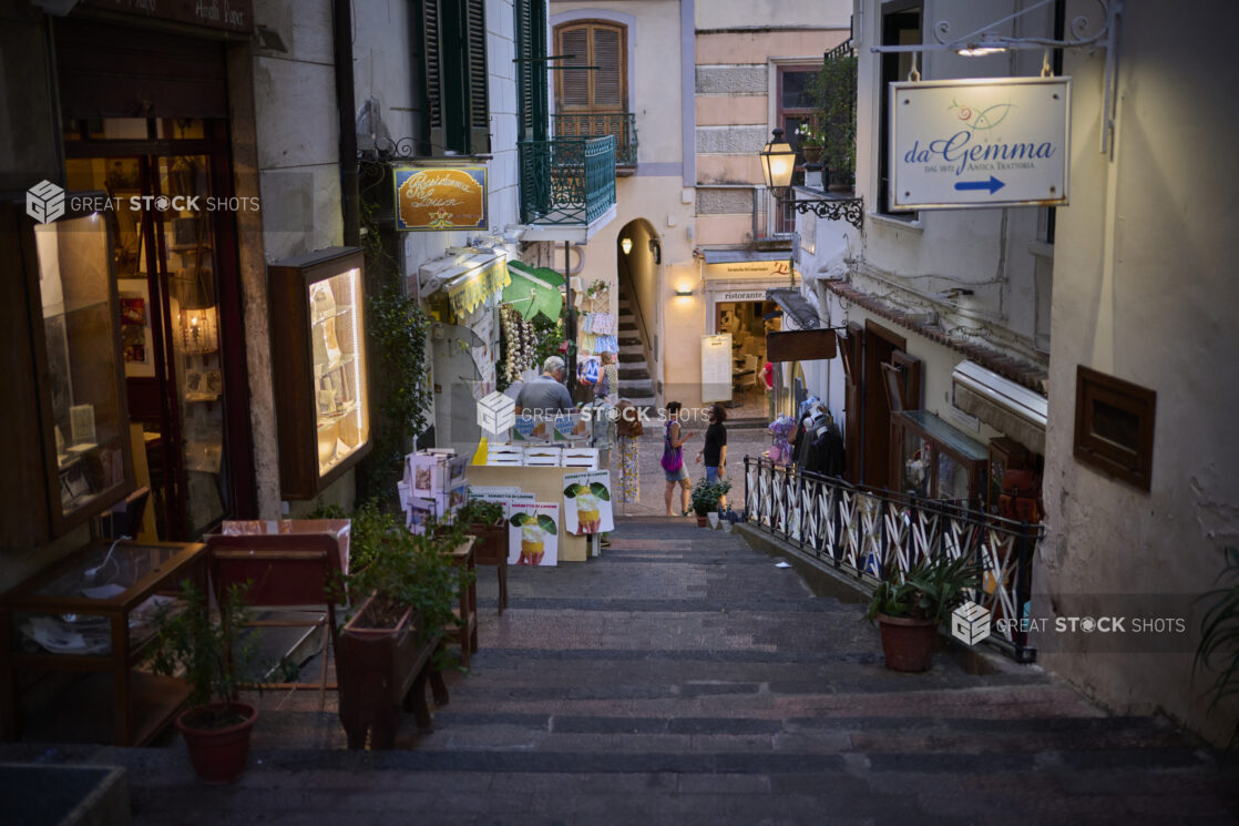 View down a shallow terraced brickwork staircase of a side street with a restaurant and stores on the Amalfi coast, Italy