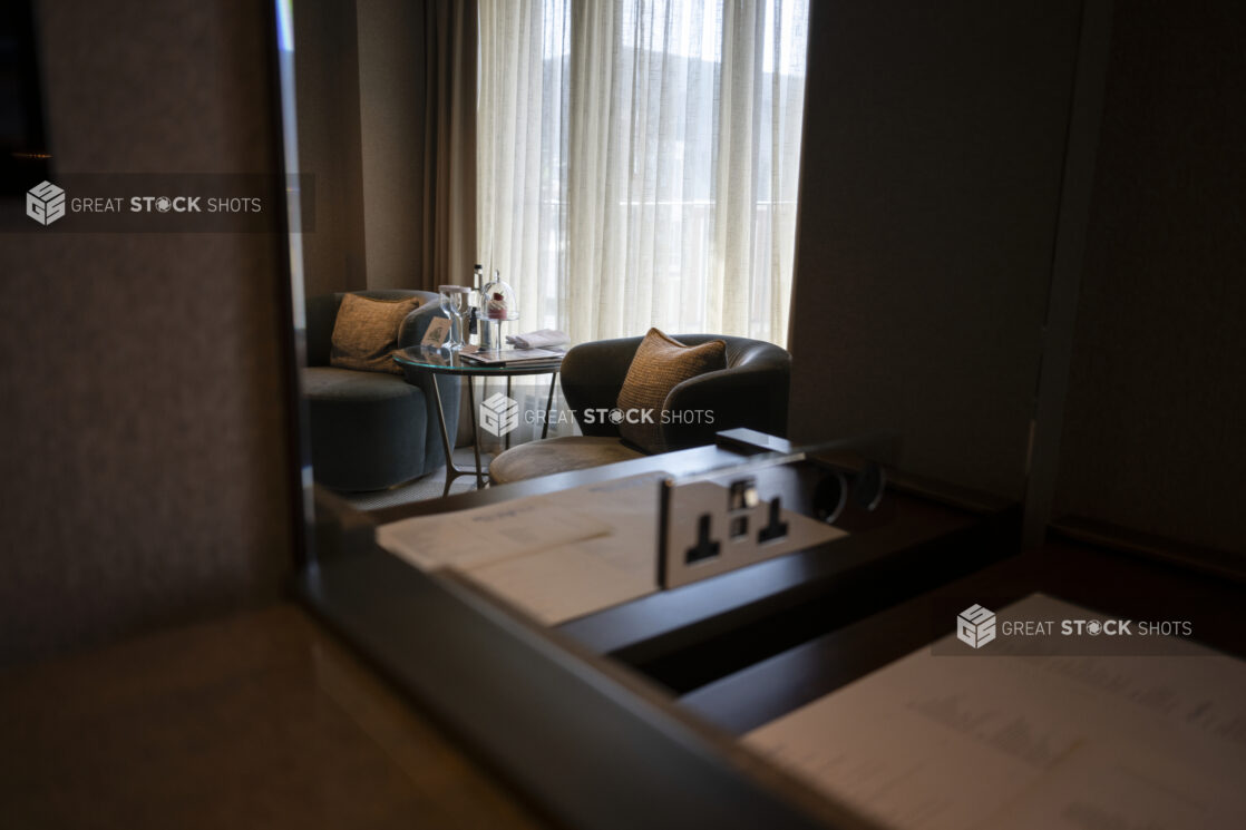 View of a hotel room sitting area in front of a window taken in a mirror