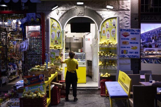 Gelato/refreshment stand in Italy at night, bright colours, with souvenir shop adjacent