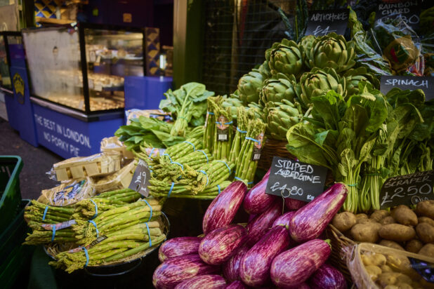Fresh vegetable display in a market with artichoke, asparagus, striped eggplant, spinach, potatoes in London, England