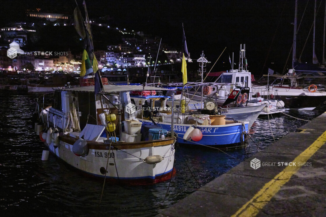 View of a harbour with boats and hillside at night in Italy