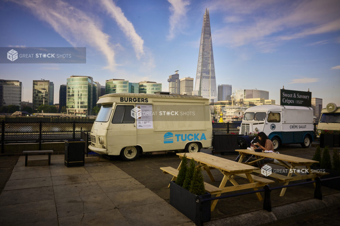 Old style food trucks along the waterfront in London, England with picnic tables and greenery surrounding