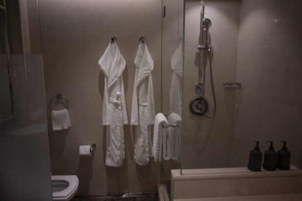 View of a bathroom with robes hanging on the wall, glassed-in shower