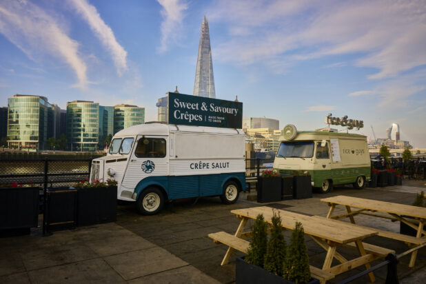 Old style food trucks along the waterfront in London, England with picnic tables