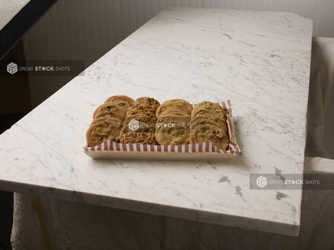 Wood catering tray of two dozen assorted cookies on a marble countertop