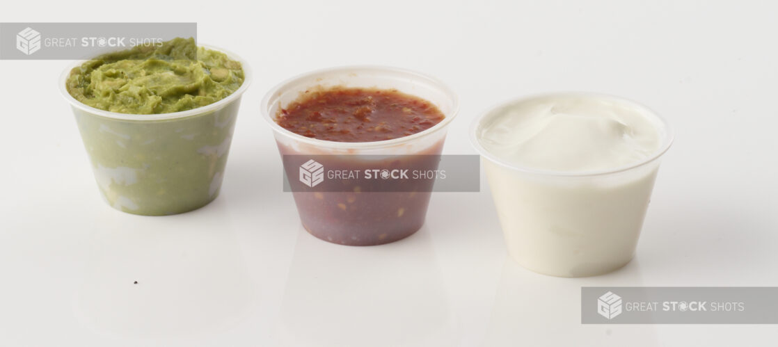 Side of guacamole salsa and sour cream on white background