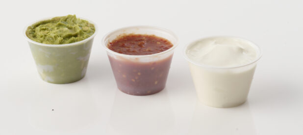 Side of guacamole salsa and sour cream on white background