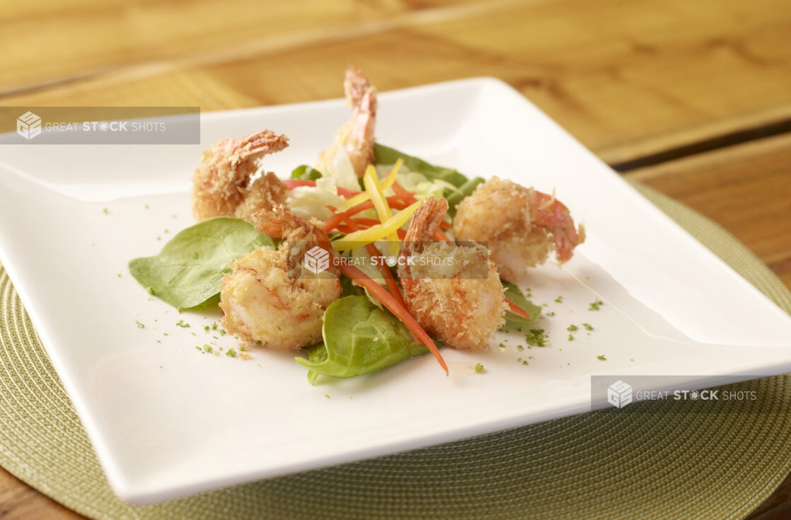 Breaded Shrimp Appetizer on Square White Dish on Wooden Table in Indoor Restaurant Setting