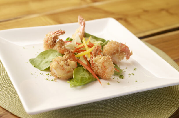 Breaded Shrimp Appetizer on Square White Dish on Wooden Table in Indoor Restaurant Setting