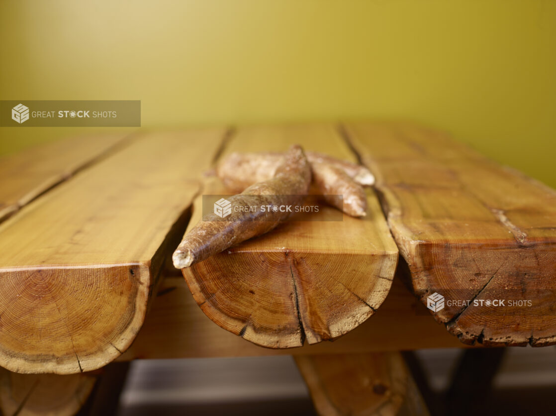 Raw Cassava Root on Wooden Table with Green Background and Bokeh Effect