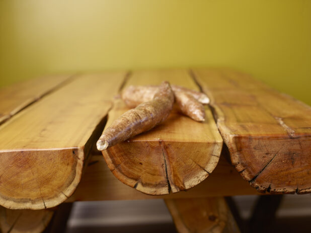 Raw Cassava Root on Wooden Table with Green Background and Bokeh Effect