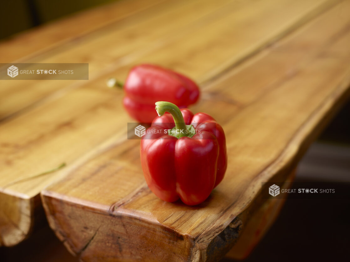 Fresh Whole Red Bell Peppers on Wooden Table with Bokeh Effect