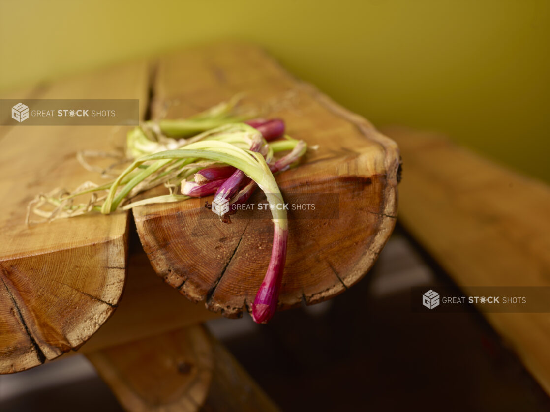 Whole Raw Green Onions with Red Bulbs on Wooden Table with Bokeh Effect