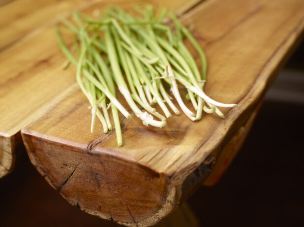 Whole Fresh Green Onion Stalks on Wooden Table with Bokeh Effect