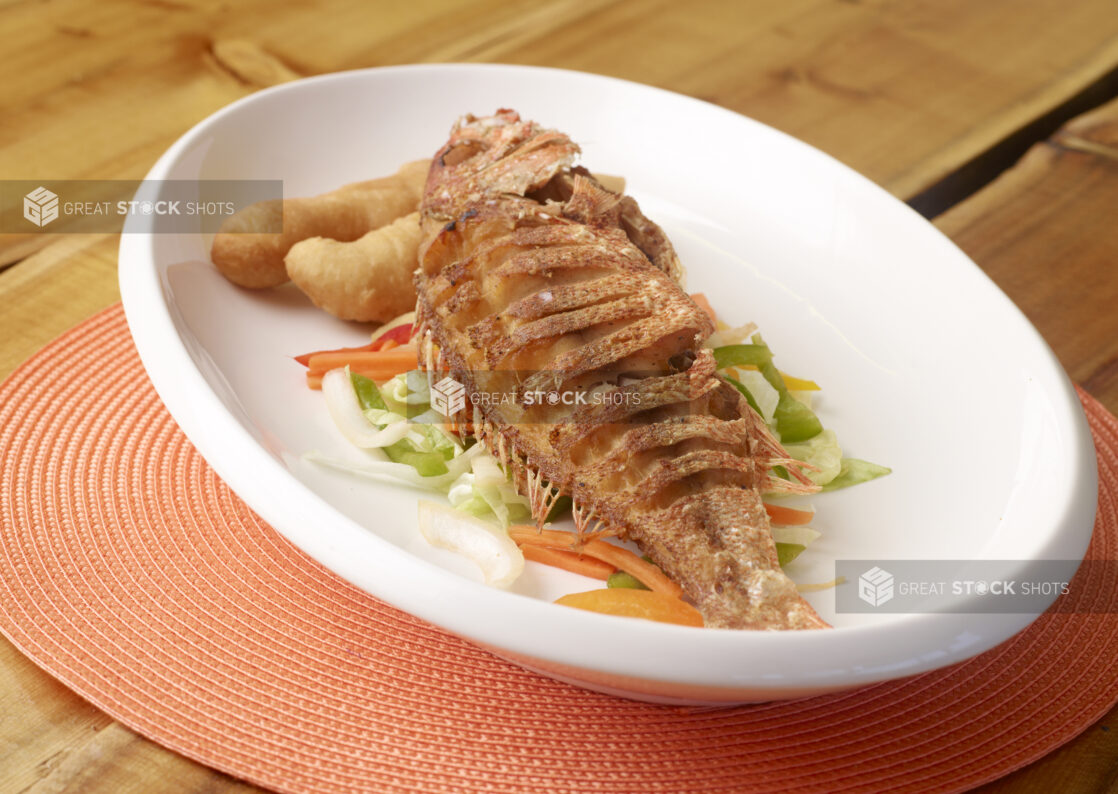 Large White Platter of Whole Oven Roasted Red Snapper with Vegetables and Fried Bread on Wooden Table - Variation