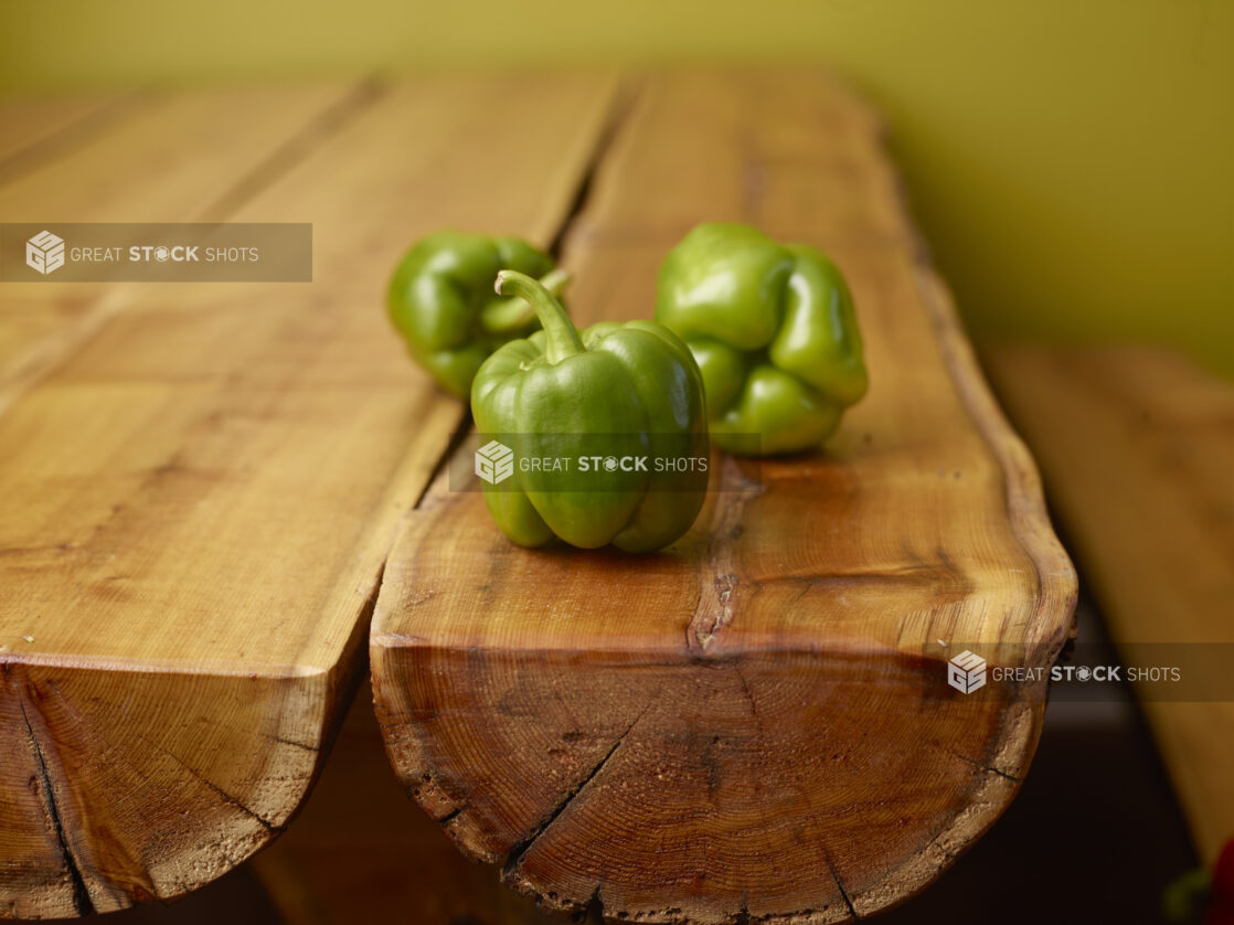 Fresh Whole Green Bell Peppers on Wooden Table with Bokeh Effect