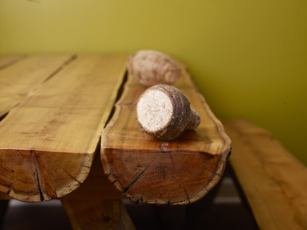 Raw Taro Root on Wooden Table with Green Background and Bokeh Effect