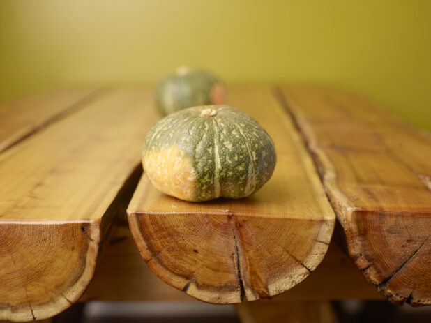 Whole Pumpkin on Wooden Table with Green Background and Bokeh Effect