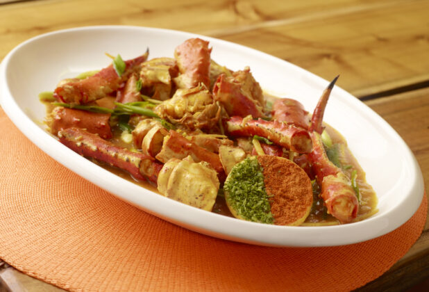 Caribbean King Crab Stew with Cracker on Large White Platter on Wooden Table with Bokeh Effect