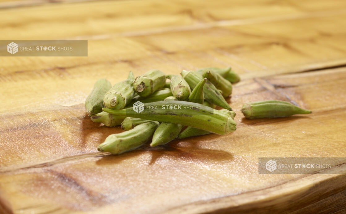 Whole Raw Okra Piled on a Wooden Table